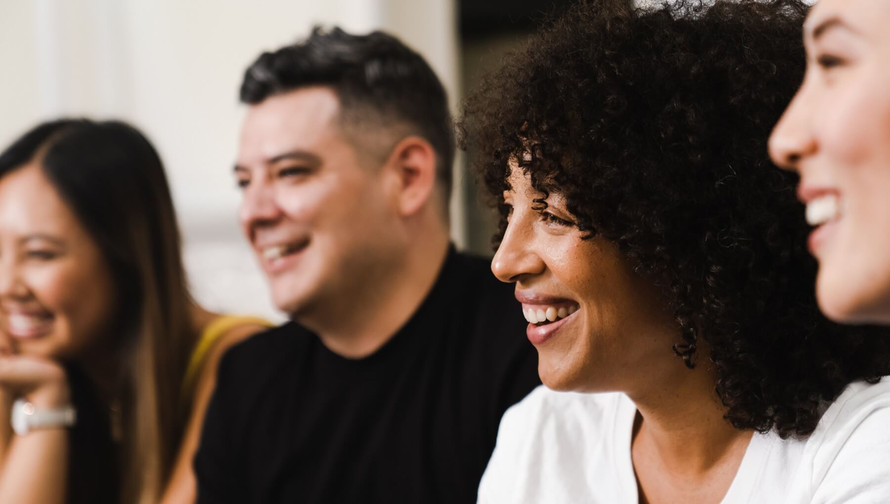 Four co-workers look to the left while smiling